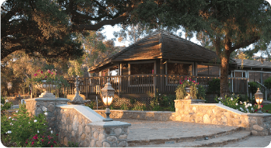 A quaint gazebo in Silverado CA, surrounded by lush gardens and lit path lamps at dusk.