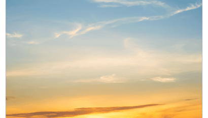 A bright Copper Sunset with golden and orange hues near the horizon, fading into a blue sky dotted with wispy, white clouds.