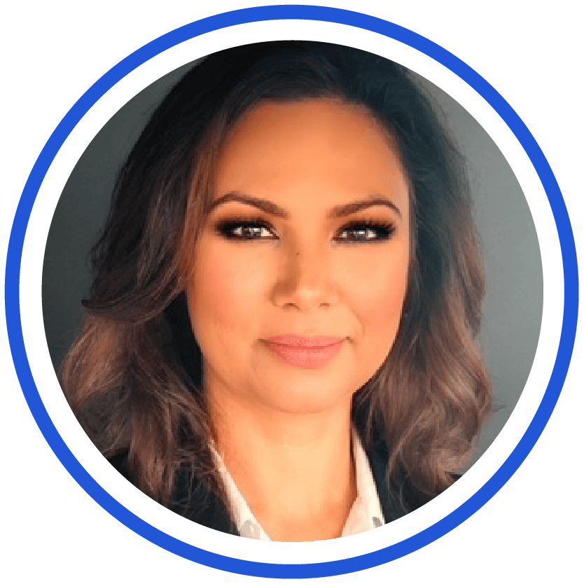 Professional headshot of a woman with long brown hair and a confident expression, wearing a white shirt and dark blazer, framed by a double blue and white circular border—exuding assurance for clients in the era of the Quantum Revolution.