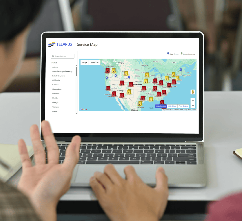 A person gestures toward a laptop displaying a Telarus service map interface, showing markers across the United States and a sidebar with a list of states—highlighting its use in Sales Applications.